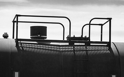 Close up of the dome and manway coverplate of a painted black tank car. Canadian vintage freight or cargo train moving in the countryside.